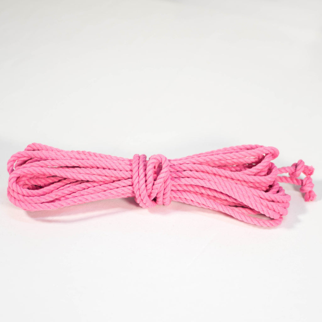 A coiled pink cotton rope with knots on the end, displayed on a white background.