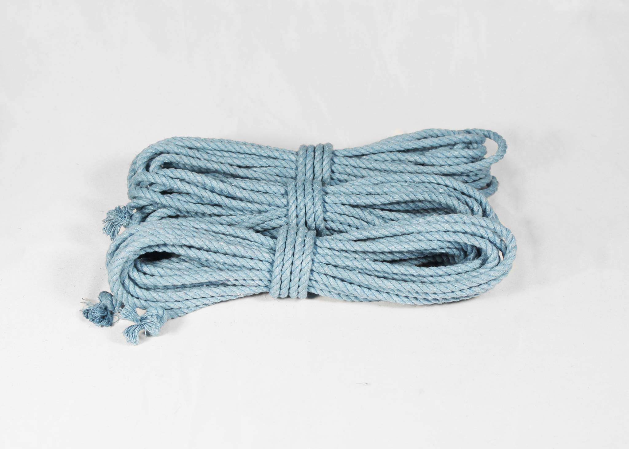 A coiled bundle of light blue braided cotton rope, photographed on a plain white background.