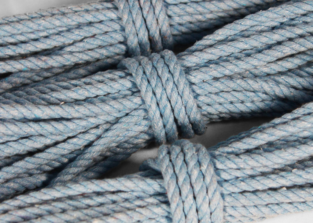 Close-up of a light blue twisted rope wrapped in a knot, showing the texture and colour of the material.