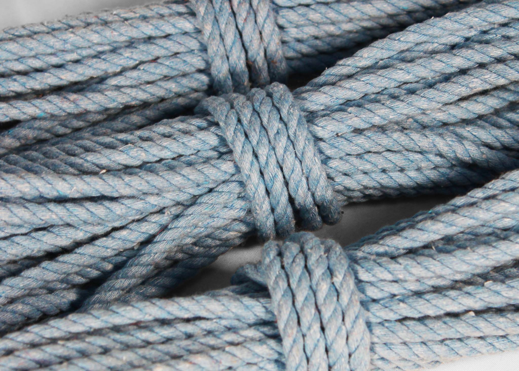 Close-up of a light blue twisted rope wrapped in a knot, showing the texture and colour of the material.