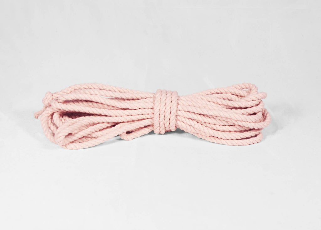 A coiled bundle of light pink braided rope, tied in the center, displayed on a clean white background.